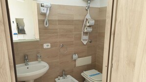 A bathroom with a sink, bidet, toilet, and a hairdryer mounted on the wall. - B&B Casa Terry (Marcianise)