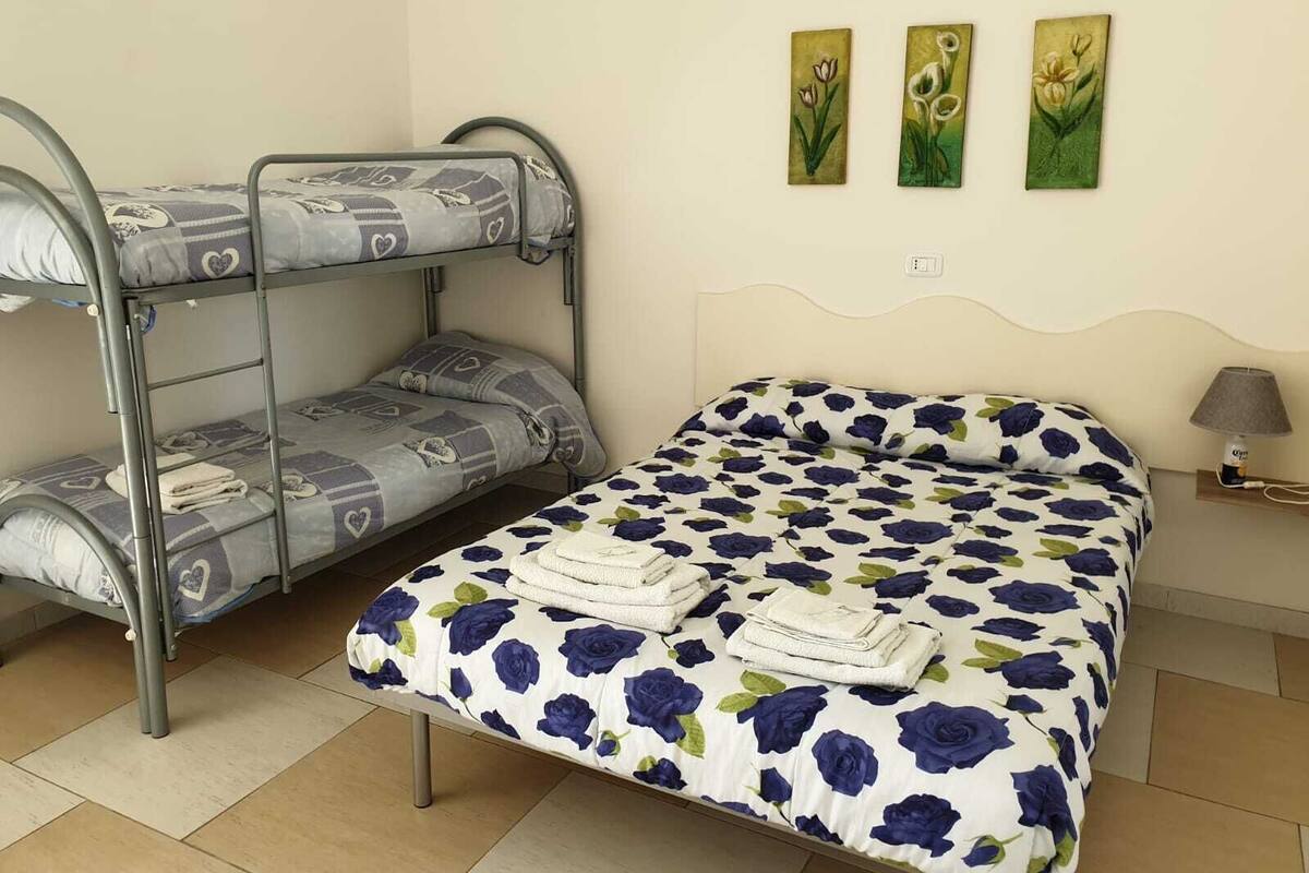 A bunk bed with a patterned bedspread and a single bed with a floral bedspread.