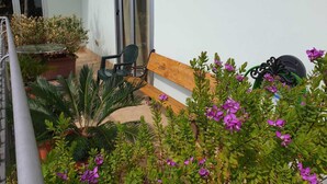 A patio with a wooden bench, a table, and potted plants. - B&B Casa Terry (Marcianise)
