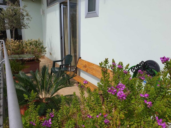 A patio with a wooden bench, a table, and potted plants. - B&B Casa Terry (Marcianise)