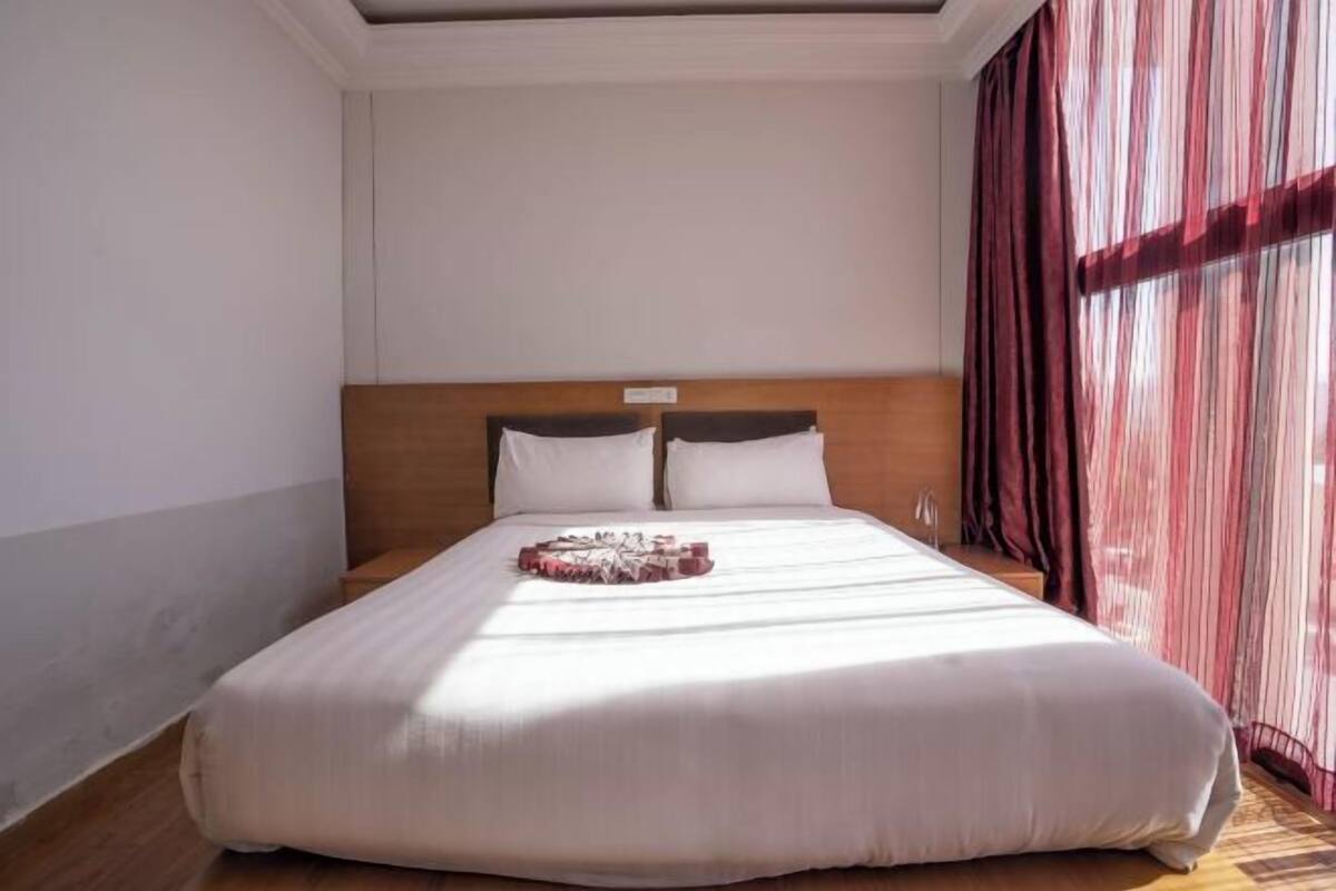 A large bed with a wooden headboard, white bedding, and a decorative object on the bed.