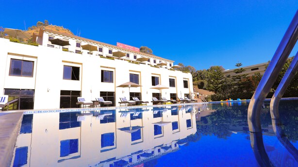 A hotel with a swimming pool, multiple balconies, and sun loungers. - Haile Resort Gondar (Gondar)