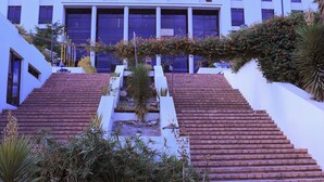 A building with a staircase leading to a gated entrance, surrounded by greenery and a clear sky. - Haile Resort Gondar (Gondar)