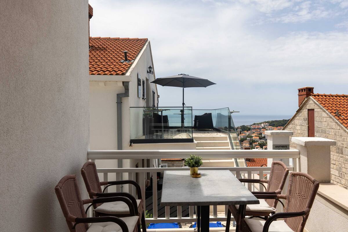 A balcony with wicker furniture, a table, and an umbrella.