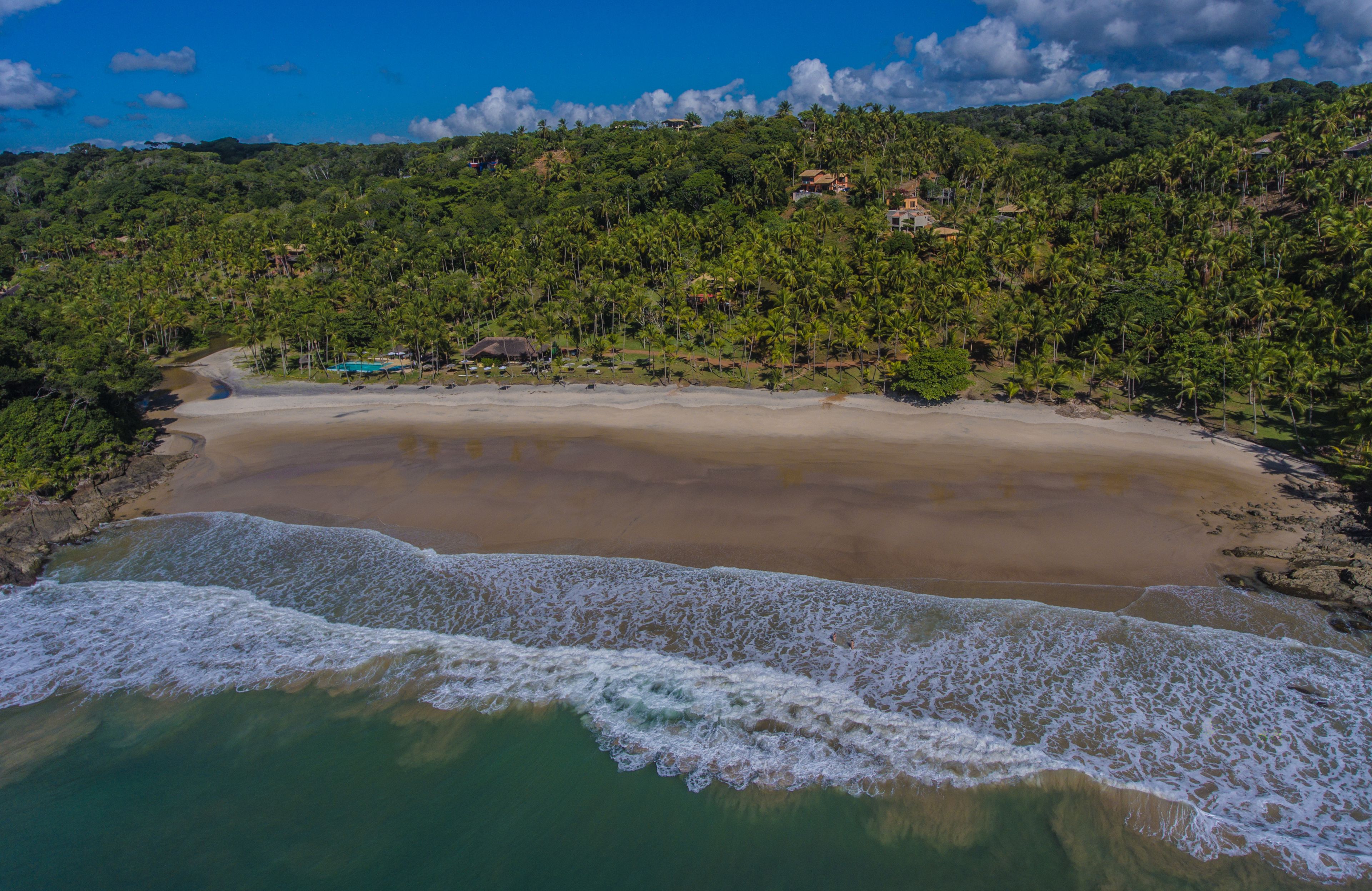 Una playa con aguas cristalinas, una orilla arenosa y un promontorio cubierto de bosque.