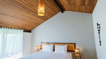 A bedroom with a wooden ceiling, a large bed with white bedding, two bedside lamps, and a small table.