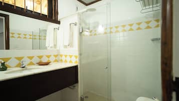 Un baño con ducha, lavamanos y espejo.