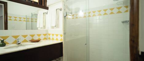 Un baño con ducha, lavamanos y espejo.