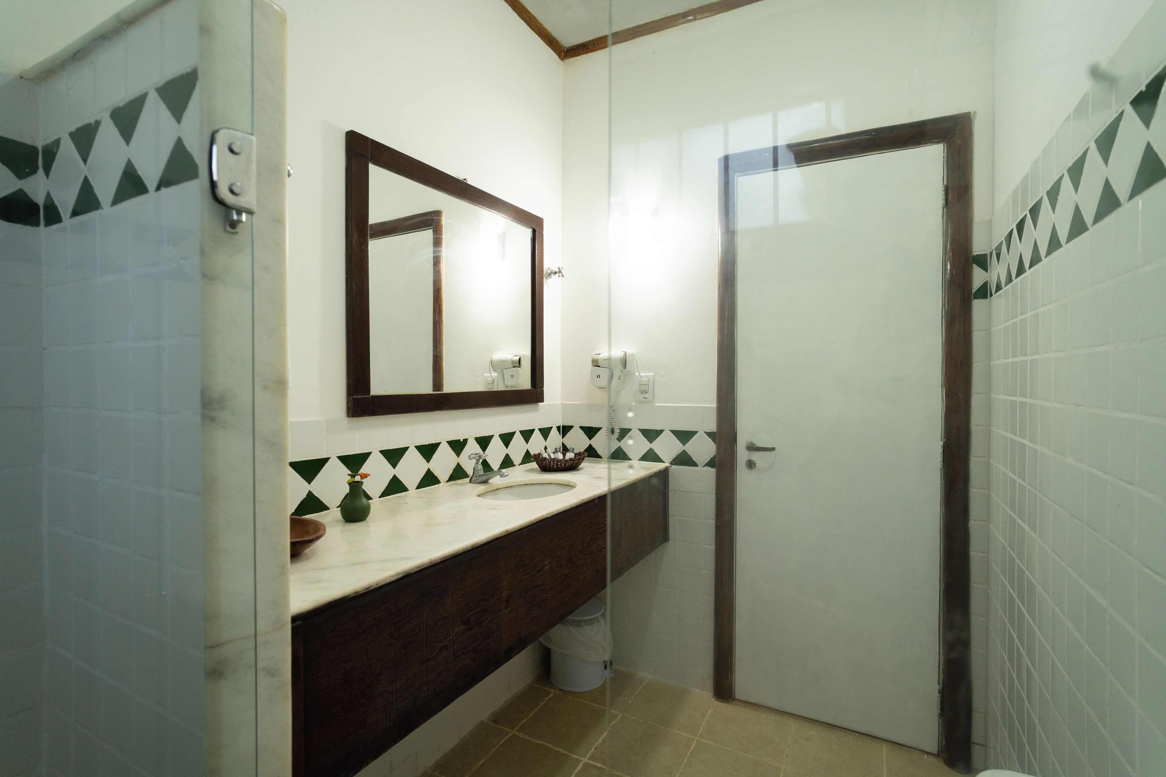 Un baño con espejo, lavamanos e inodoro.