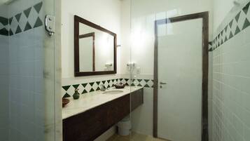 Un baño con espejo, lavamanos e inodoro.