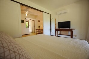 A hotel room with a bed, a television on a wooden stand, and an air conditioning unit on the wall. - São José Beach Club & Residence (Itacaré)