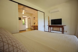 Habitación de hotel con una cama, un televisor sobre un mueble de madera y un equipo de aire acondicionado en la pared.
