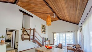Un espacio habitable amplio con una escalera de madera, una mesa de comedor con sillas y un ventilador de techo.