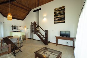 A spacious living area with a wooden staircase, a dining table, and a television. - São José Beach Club & Residence (Itacaré)
