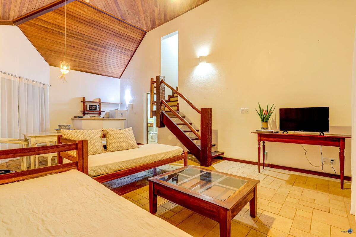 Une pièce confortable avec un lit, une table en bois, un téléviseur et un escalier.