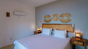 Quarto com uma cama grande, duas mesas de cabeceira com luminárias, uma luz de teto e decoração na parede.