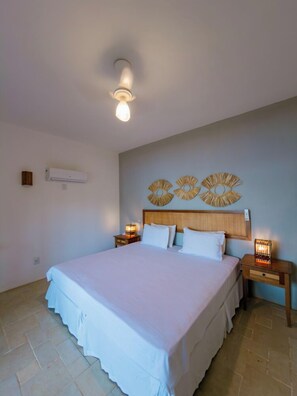 Un dormitorio con una cama grande, dos mesitas de noche con lámparas, una lámpara de techo y decoración en la pared.