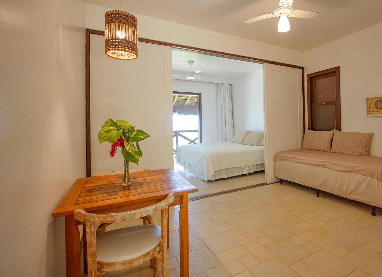 Una habitación con una cama, un sofá, una mesa con una planta y un ventilador de techo.