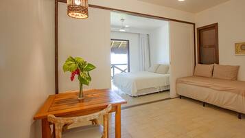 Una habitación con una cama, un sofá, una mesa con una planta y un ventilador de techo.