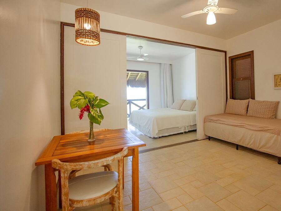 Una habitación con una cama, un sofá, una mesa con una planta y un ventilador de techo.