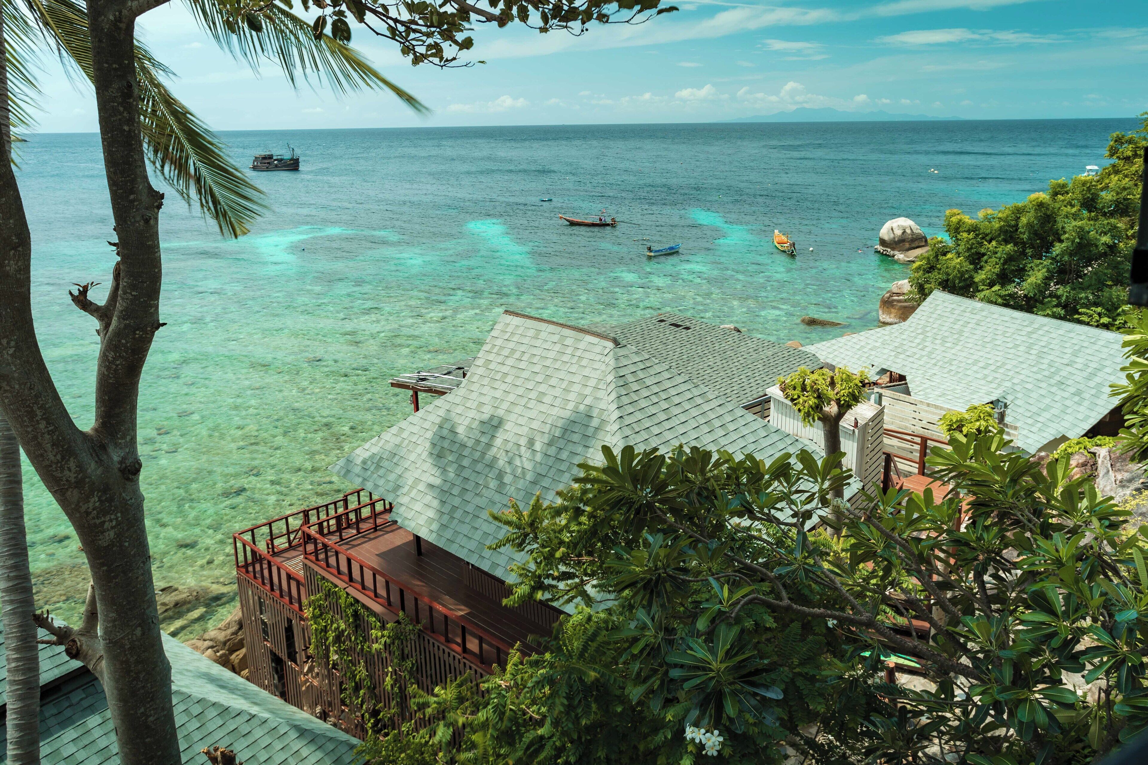 A coastal property with a view of the sea, featuring a wooden deck and a small boat dock.