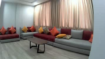 A modern living room with a sectional sofa, a coffee table, and a large window with curtains.