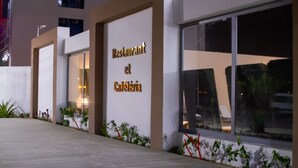 Un restaurante y cafetería con fachada moderna, amplios ventanales y un exterior bien iluminado.