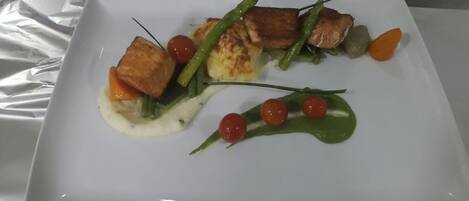 Un plato blanco con una porción de comida, que incluye tofu, judías verdes y tomates cherry.