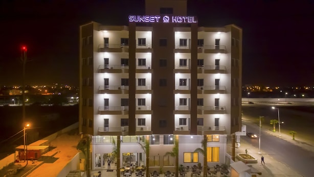 Un hotel de varios pisos con piscina, zona de estar al aire libre y una entrada bien iluminada.