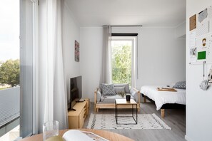 A modern, well-lit bedroom with a large window, a sofa, a bed, and a bedside table with a tray. - Bob W Tallinn Telliskivi (Tallinn)