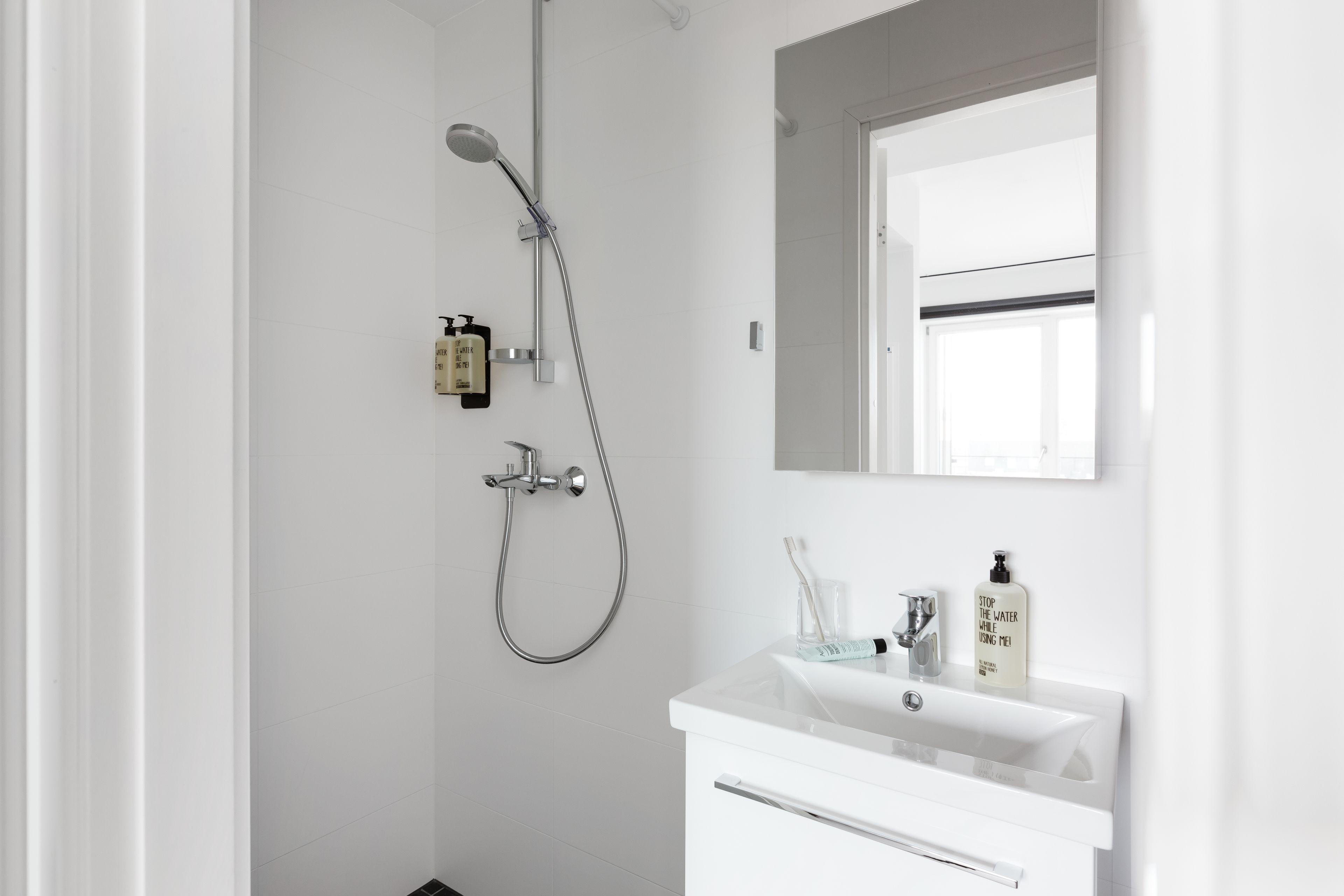 A modern bathroom with a shower, a sink, and a mirror.