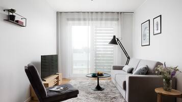 Uma sala de estar moderna com um sofá, uma poltrona, uma mesa de centro e uma televisão.