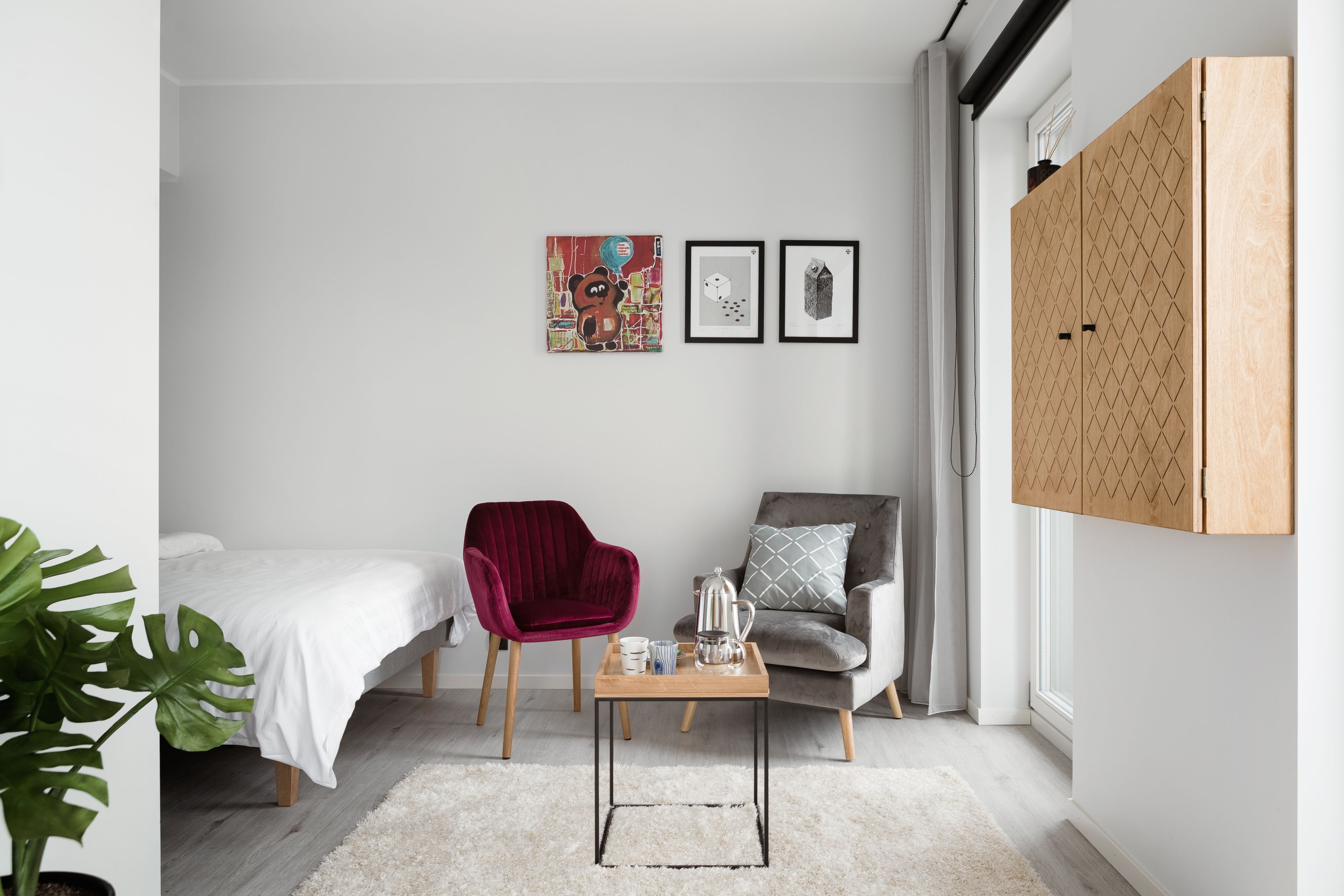 A modern bedroom with a bed, two chairs, a coffee table, and artwork on the wall.