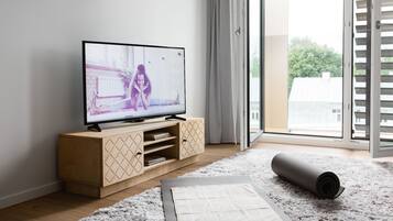 Een moderne woonkamer met een flatscreen televisie op een houten kast, een yogamat en een zacht vloerkleed.