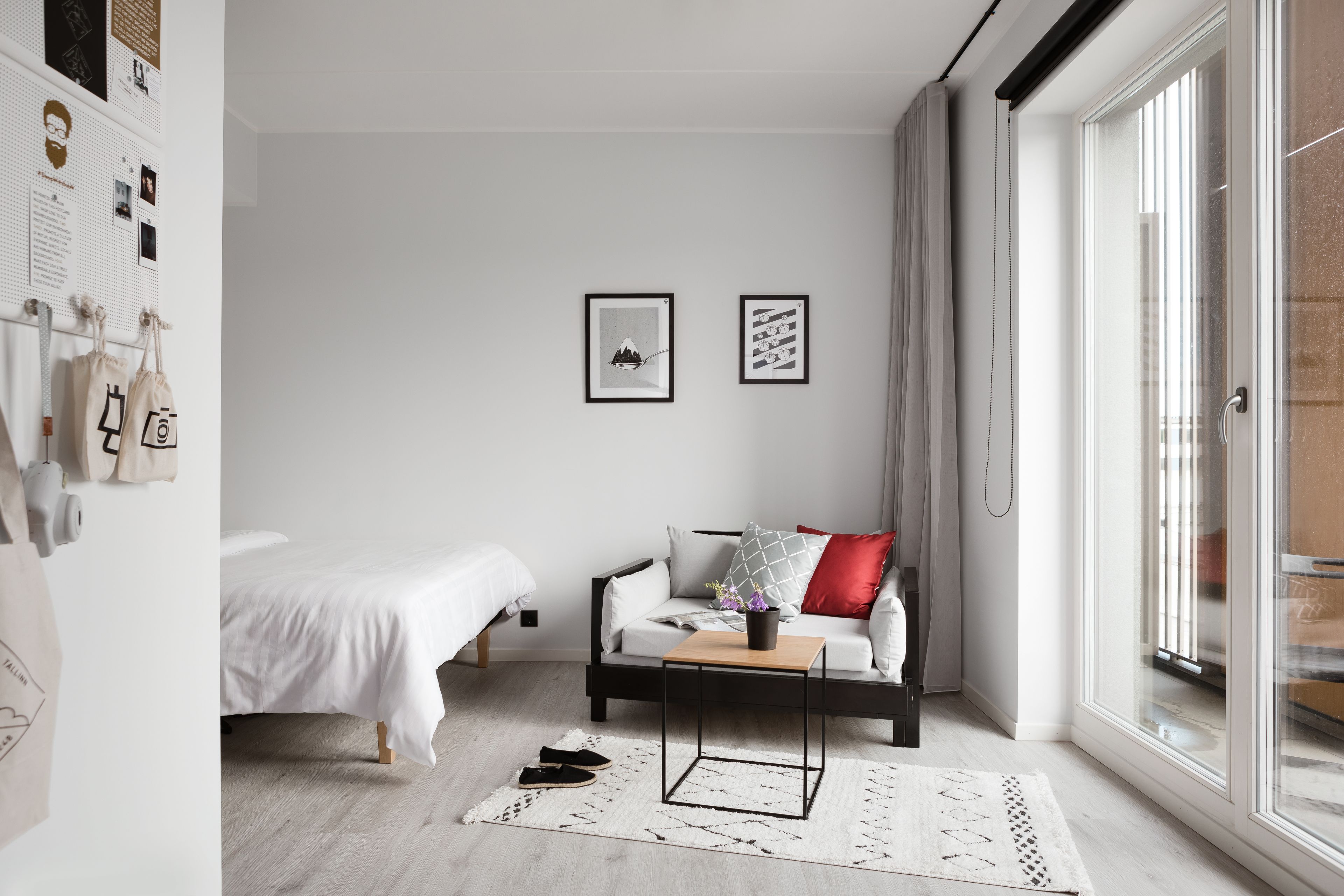 Une chambre moderne avec un lit, un canapé, une table basse et une grande fenêtre.