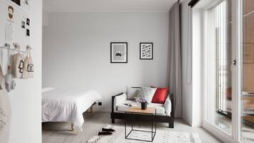 Un dormitorio moderno con cama, sofá, una mesa de centro y un ventanal grande.