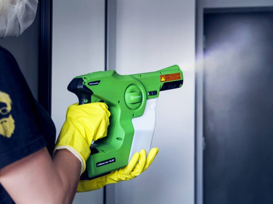 A person holding a green cleaning device with a warning label.