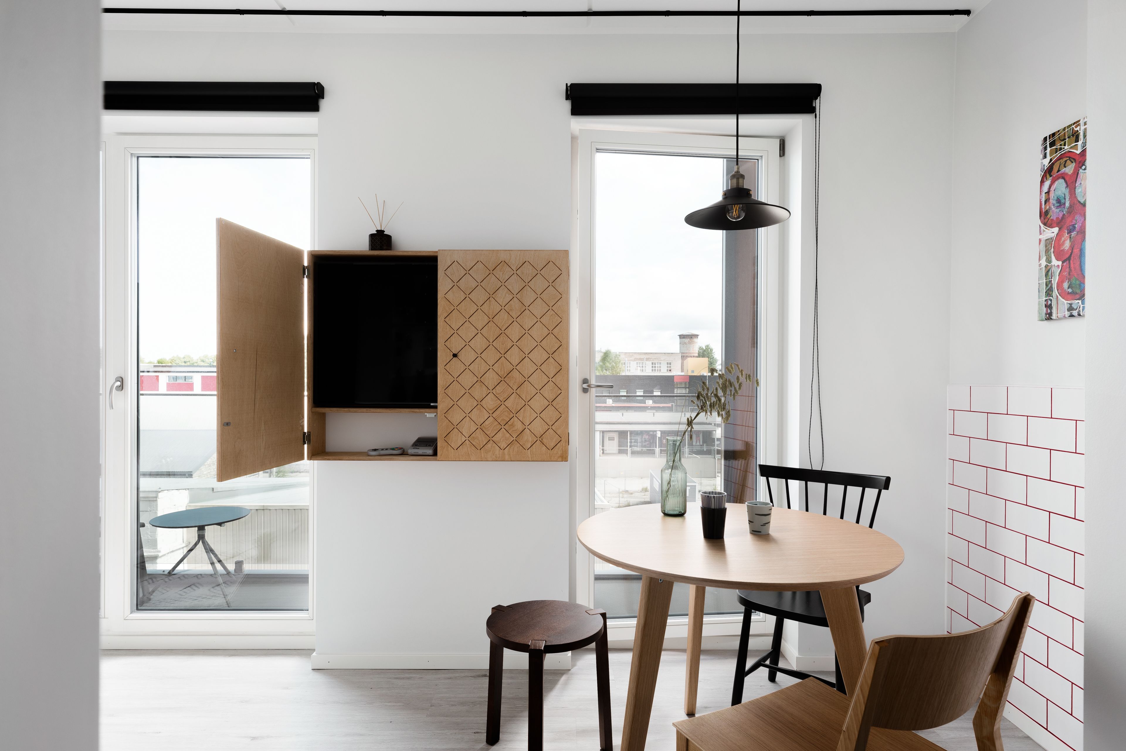 A modern kitchen with a round table, wooden chairs, and a pendant light.