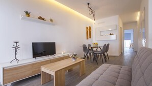 A modern living room with a flat-screen TV, a wooden coffee table, a gray sofa, and a dining area with a glass table and chairs. - B38 - Tamar 2 Bed Apartment in Lagos by DreamAlgarve (Lagos)