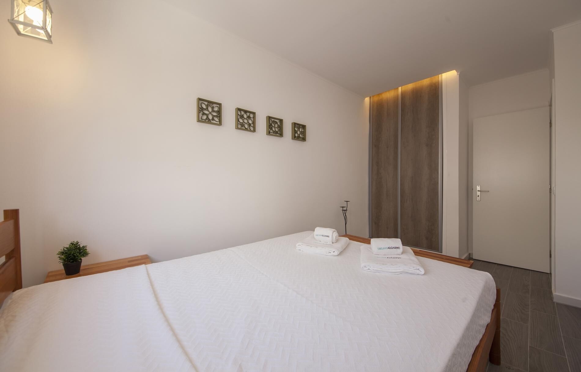 Habitación de hotel con una cama grande, una pequeña planta en maceta y una puerta con panel de madera.