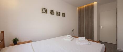 Habitación de hotel con una cama grande, una pequeña planta en maceta y una puerta con panel de madera.