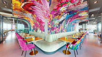 Un restaurante moderno con un mural vibrante, un área de asientos curva y vistas panorámicas de la ciudad.