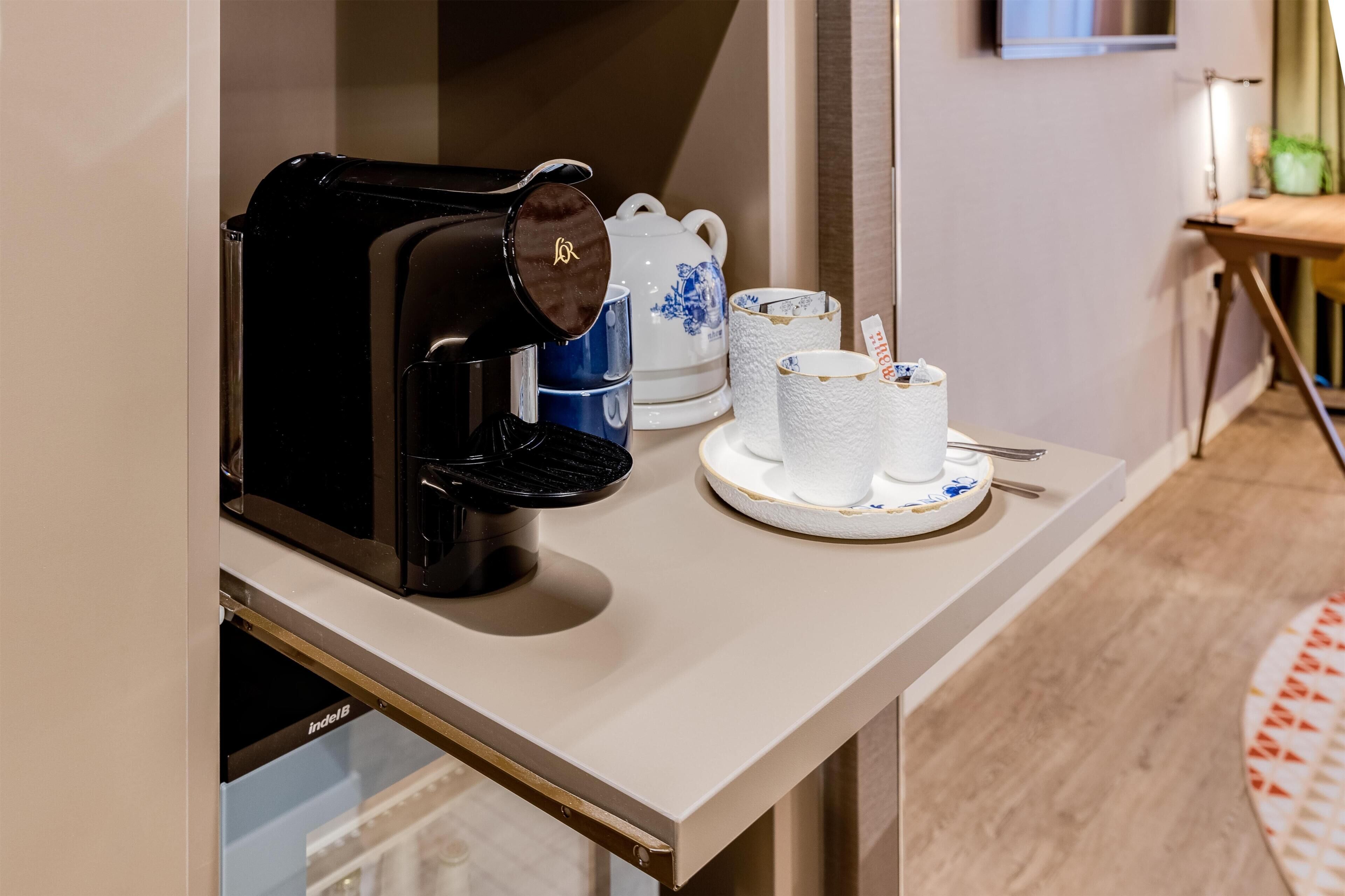 Ett litet kök med en kaffebryggare, tekanna, koppar och ett bricka.