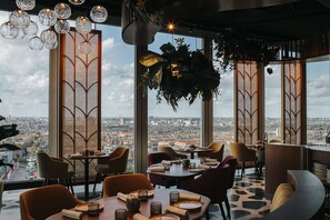 A restaurant with a city view, modern decor, and a variety of seating options. - nhow Amsterdam RAI (Amsterdam)