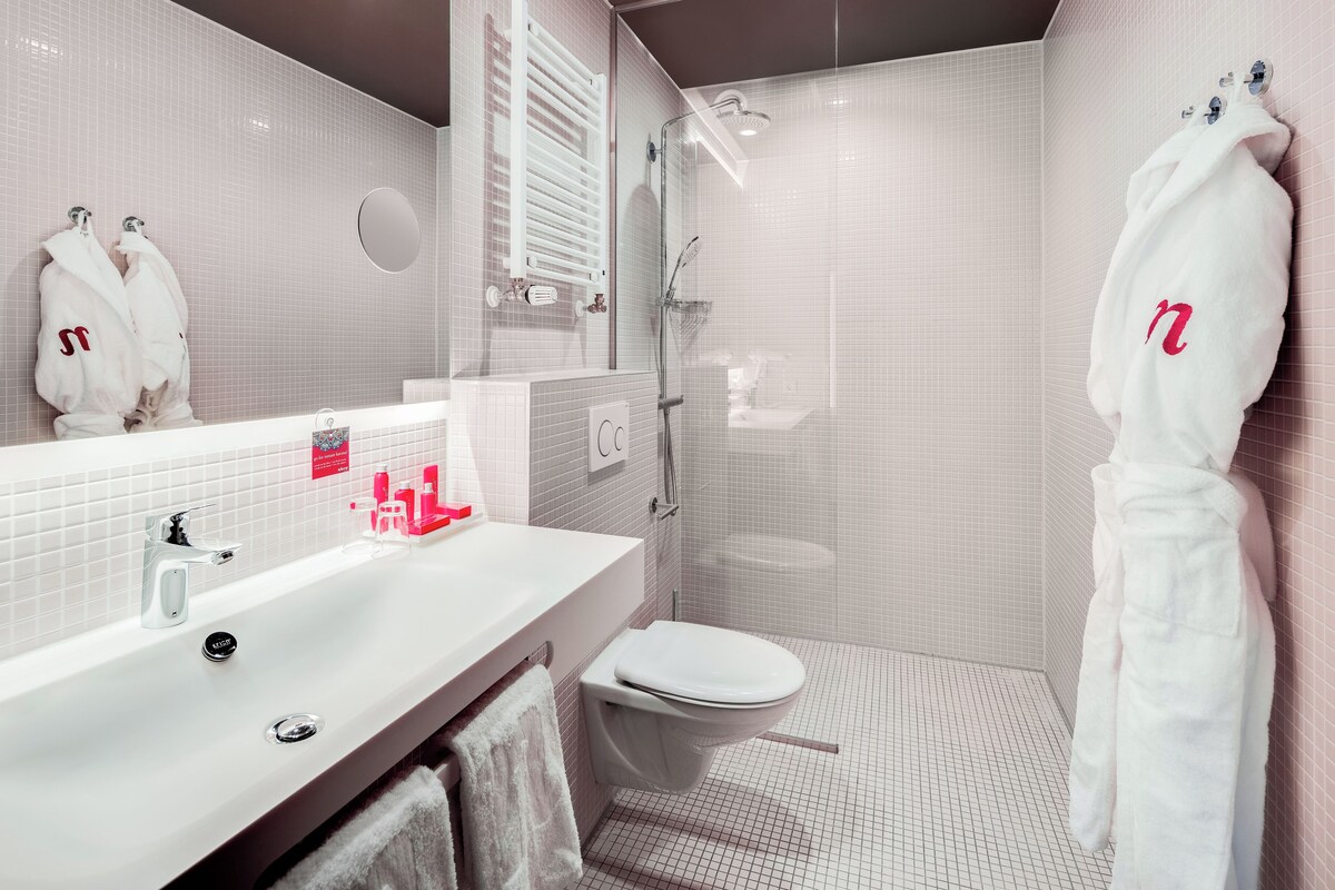 Un baño moderno con un lavamanos blanco, un inodoro y una zona de ducha.