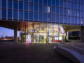 Un edificio moderno con fachada de vidrio, puerta giratoria y interior bien iluminado.