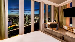 A hotel room with a large bed, a desk, and a TV. It has a city view through large windows. - nhow Amsterdam RAI (Amsterdam)