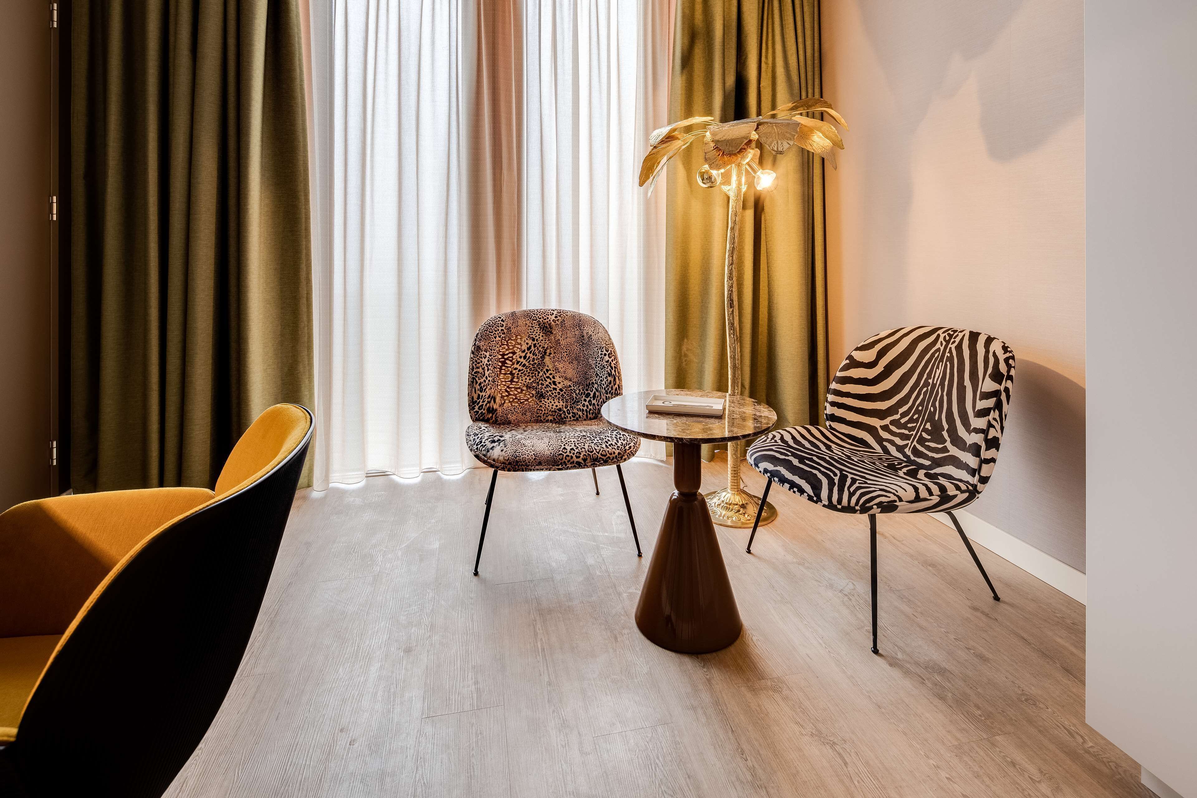 A modern room with a round table, two patterned chairs, and a floor lamp.
