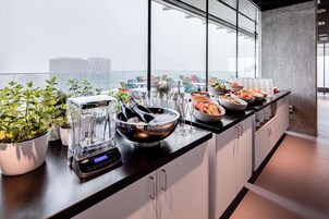 Une cuisine moderne dotée d’un grand îlot central, d’un mixeur, de bols et de plantes en pot.