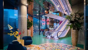 A modern indoor space with a colorful floor design, seating areas, and an escalator. - nhow Amsterdam RAI (Amsterdam)